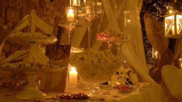 Een buffettafel met diverse gerechten en desserts, verlicht door kaarsen en lampionnen.