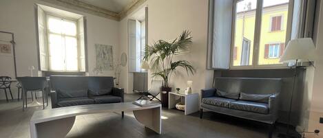 Un salón espacioso con diseño moderno, que incluye un sofá gris, una mesa de centro y una planta en maceta.