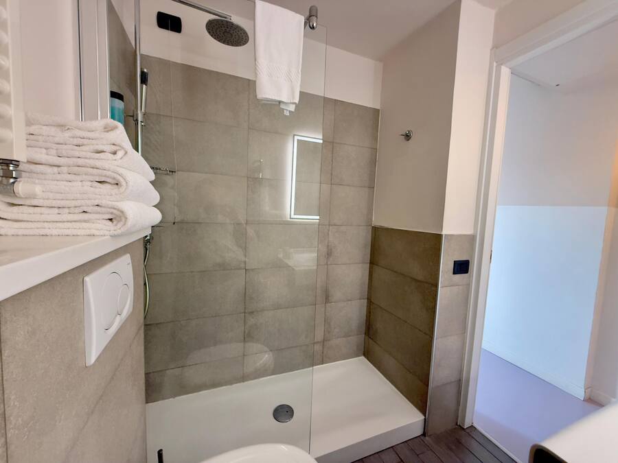 A modern bathroom with a glass-enclosed shower, a white sink, and a towel rack with folded towels.