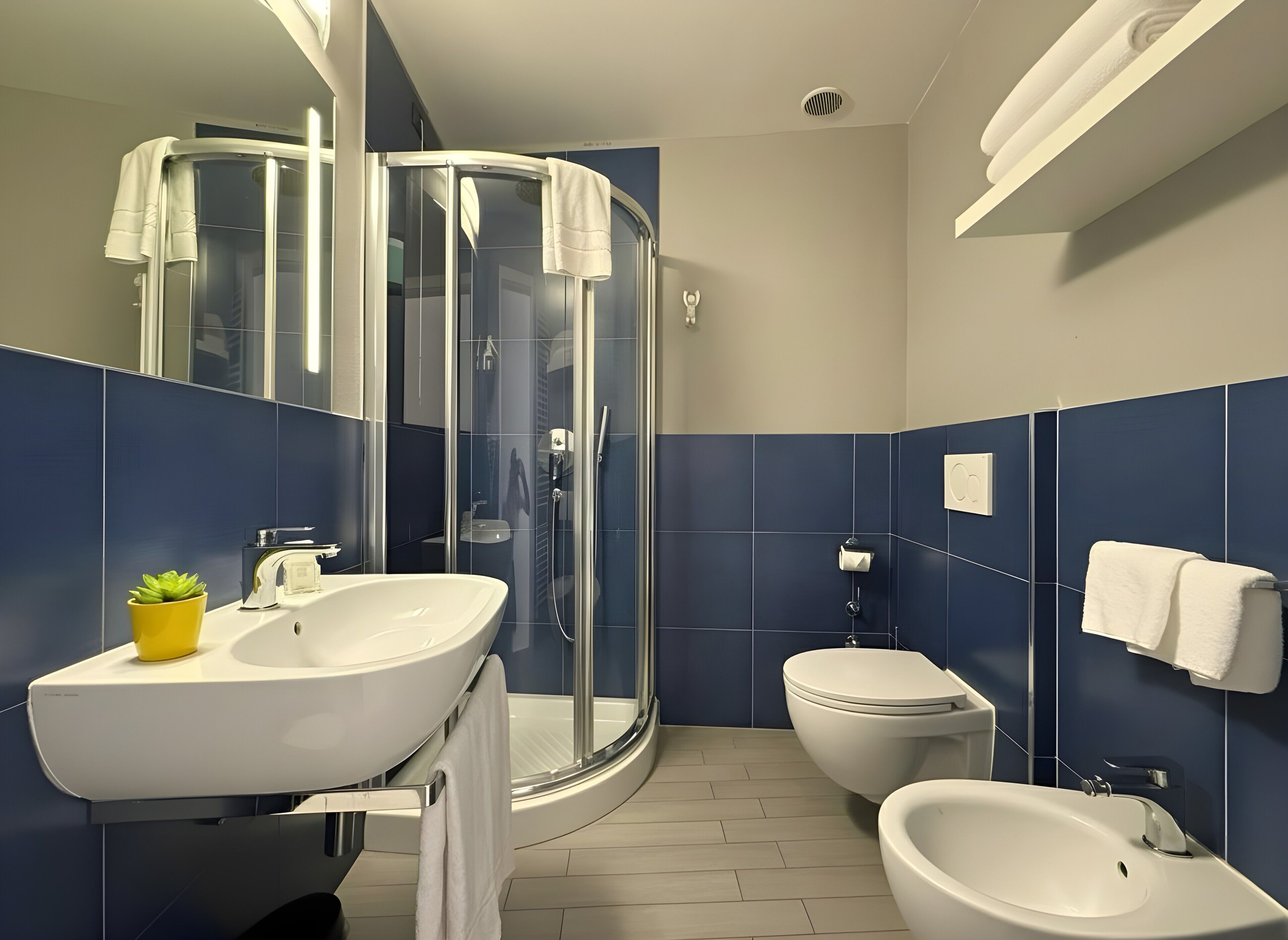 A modern bathroom with a curved shower enclosure, a white sink, a bidet, and a toilet.