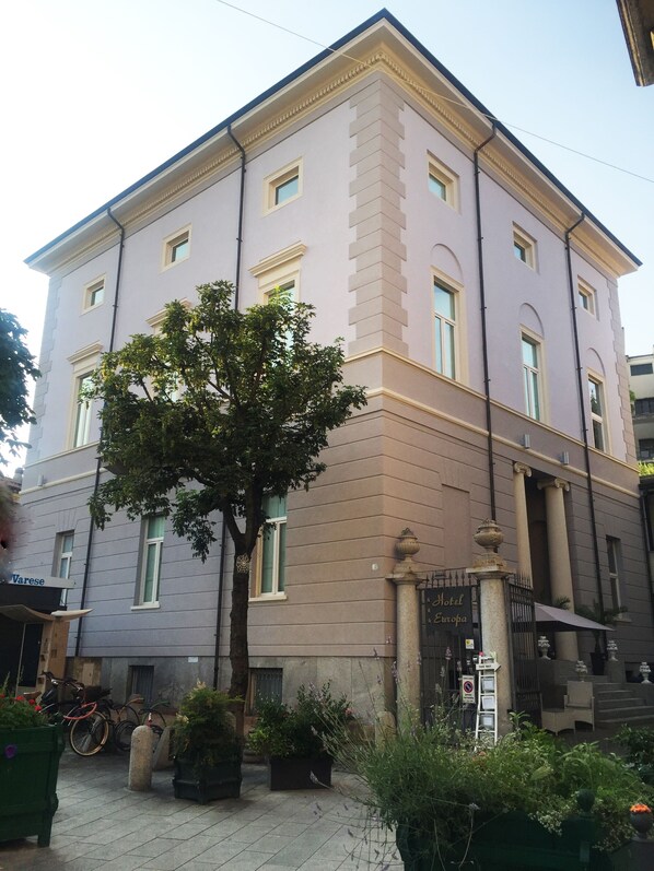 Un immeuble à plusieurs étages de style architectural classique, doté d’une entrée centrale ornée d’une colonne décorative et d’une enseigne indiquant « Hôtel Europa ».