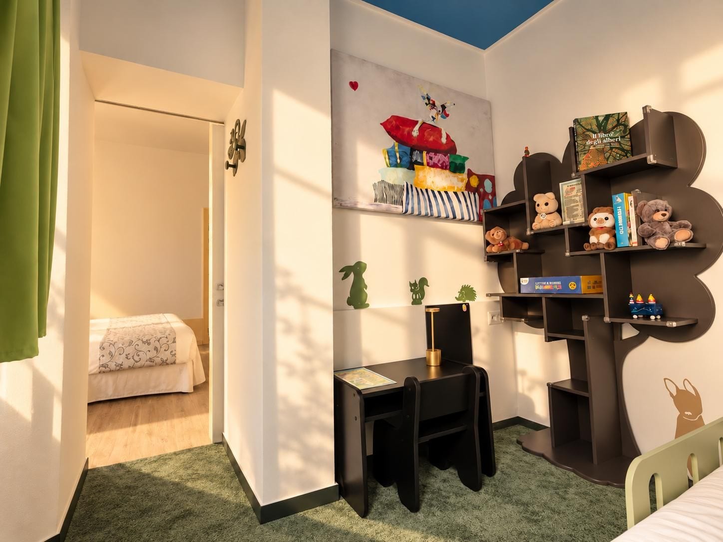 Habitación infantil con cama, escritorio y estanterías llenas de juguetes y libros.