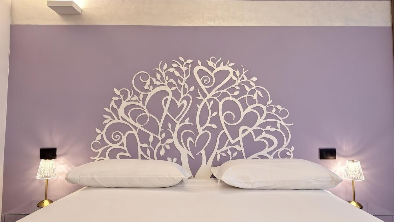 A bedroom with a decorative headboard, two bedside lamps, and a bed with white bedding.