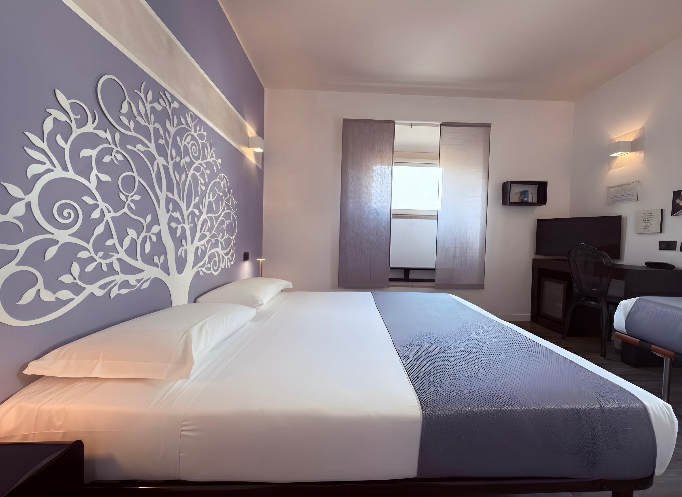 Una habitación de hotel con una cama, un escritorio, una silla y un televisor.