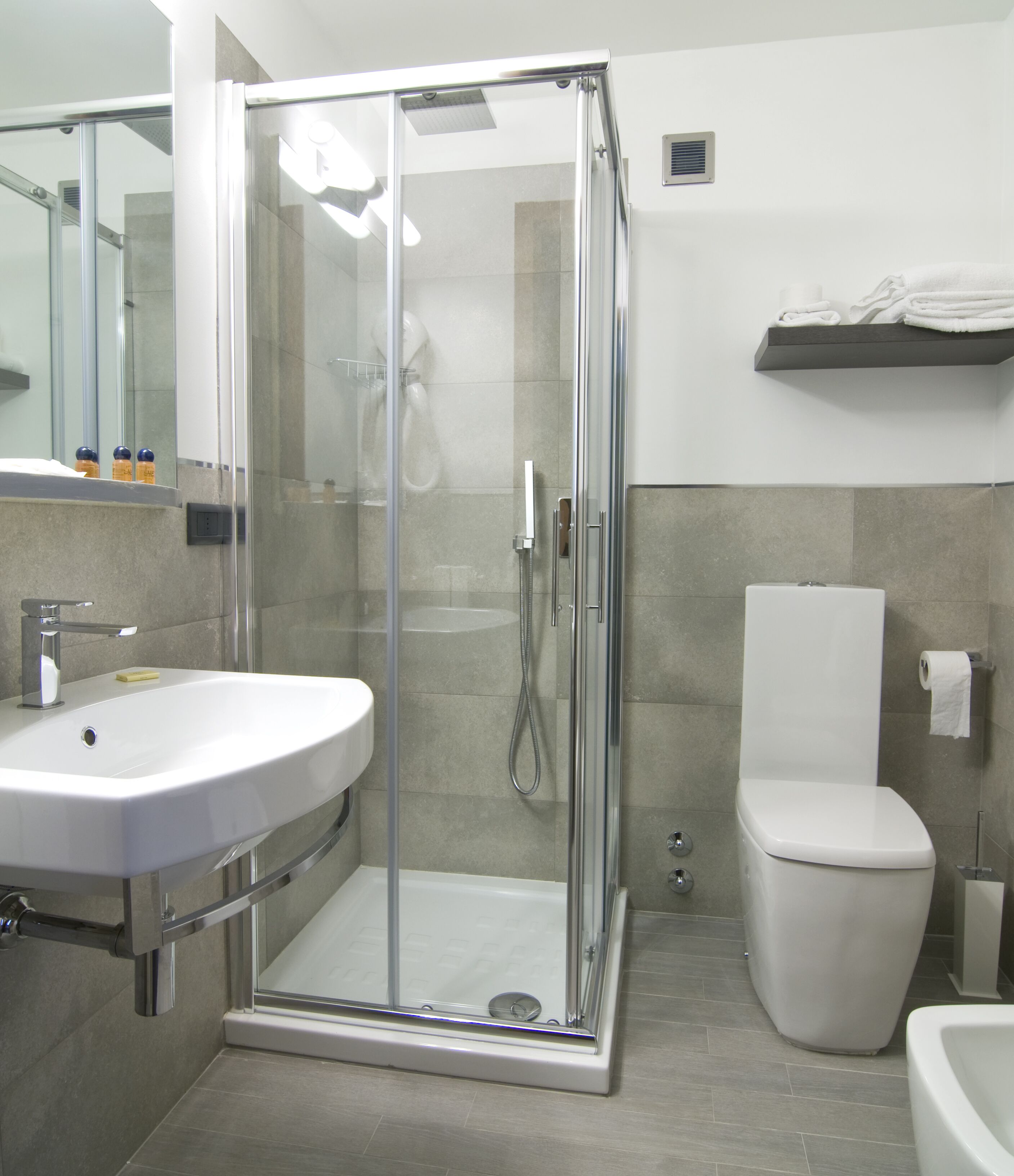 A modern bathroom with a glass-enclosed shower, a white sink, and a toilet.