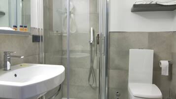 A modern bathroom with a glass-enclosed shower, a white sink, and a toilet.