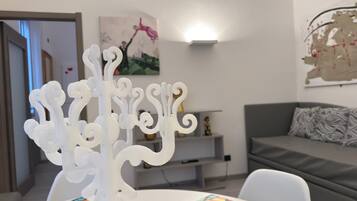 Una sala de estar moderna con un candelabro blanco sobre una mesa, un sofá gris y un mantel colorido.