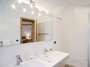 A modern bathroom with a large mirror, two sinks, and a towel rack.