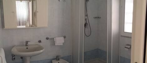 Un baño con lavamanos, bidé y ducha.
