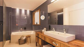 A modern bathroom with two sinks, a large mirror, and a wooden vanity.