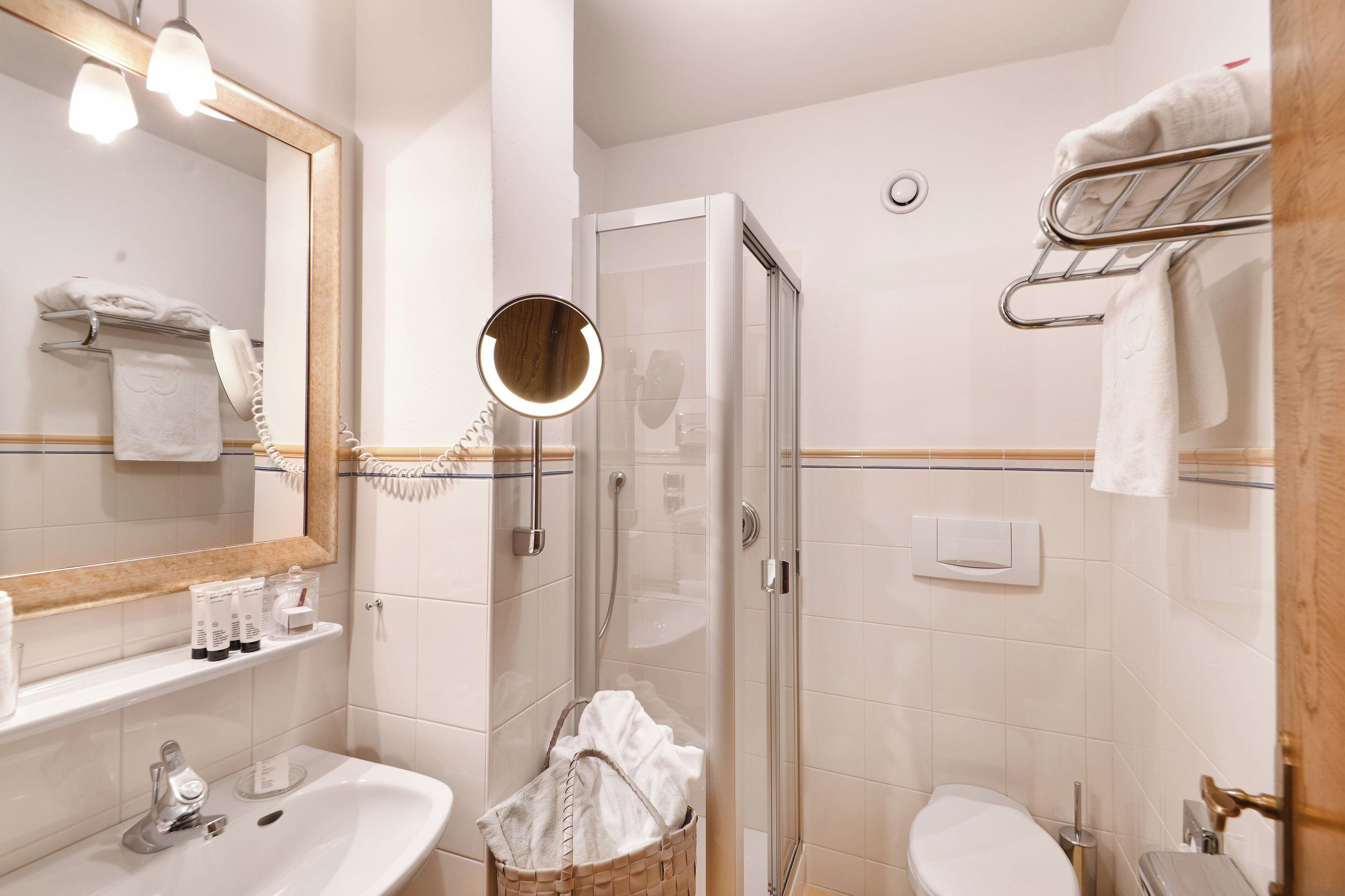 Un baño con lavamanos, espejo, ducha y toallero.