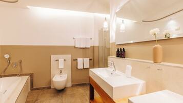 Un baño moderno con bañera, bidé y tocador con espejo.