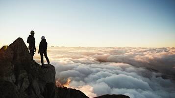 Two people standing on a rocky peak overlooking a sea of clouds.