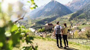 A couple standing on a hill overlooking a valley with mountains in the background. - Hotel Hohenwart (Schenna)