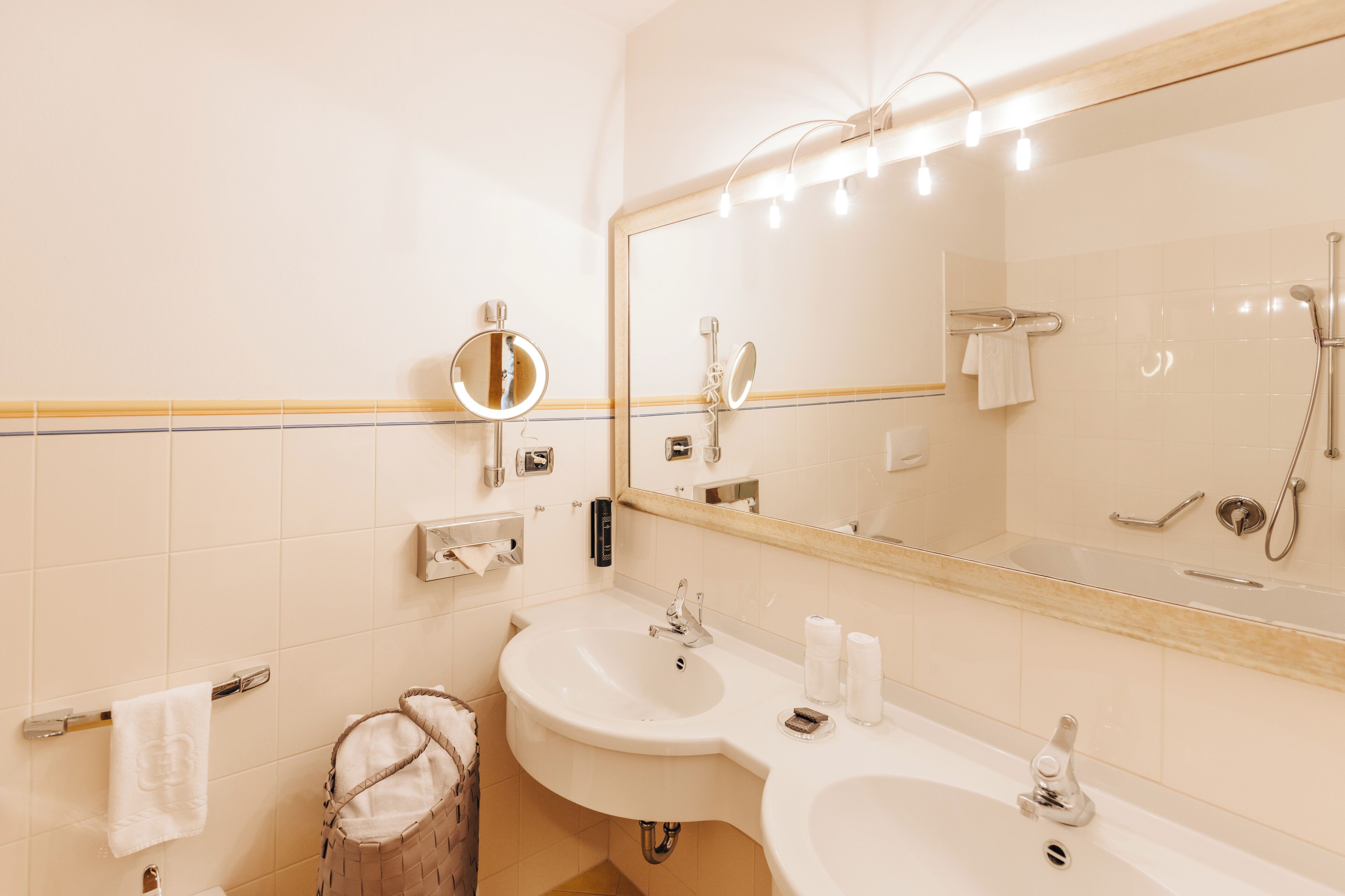 Ein modernes Badezimmer mit zwei Waschbecken, einem großen Spiegel und einer Dusche.