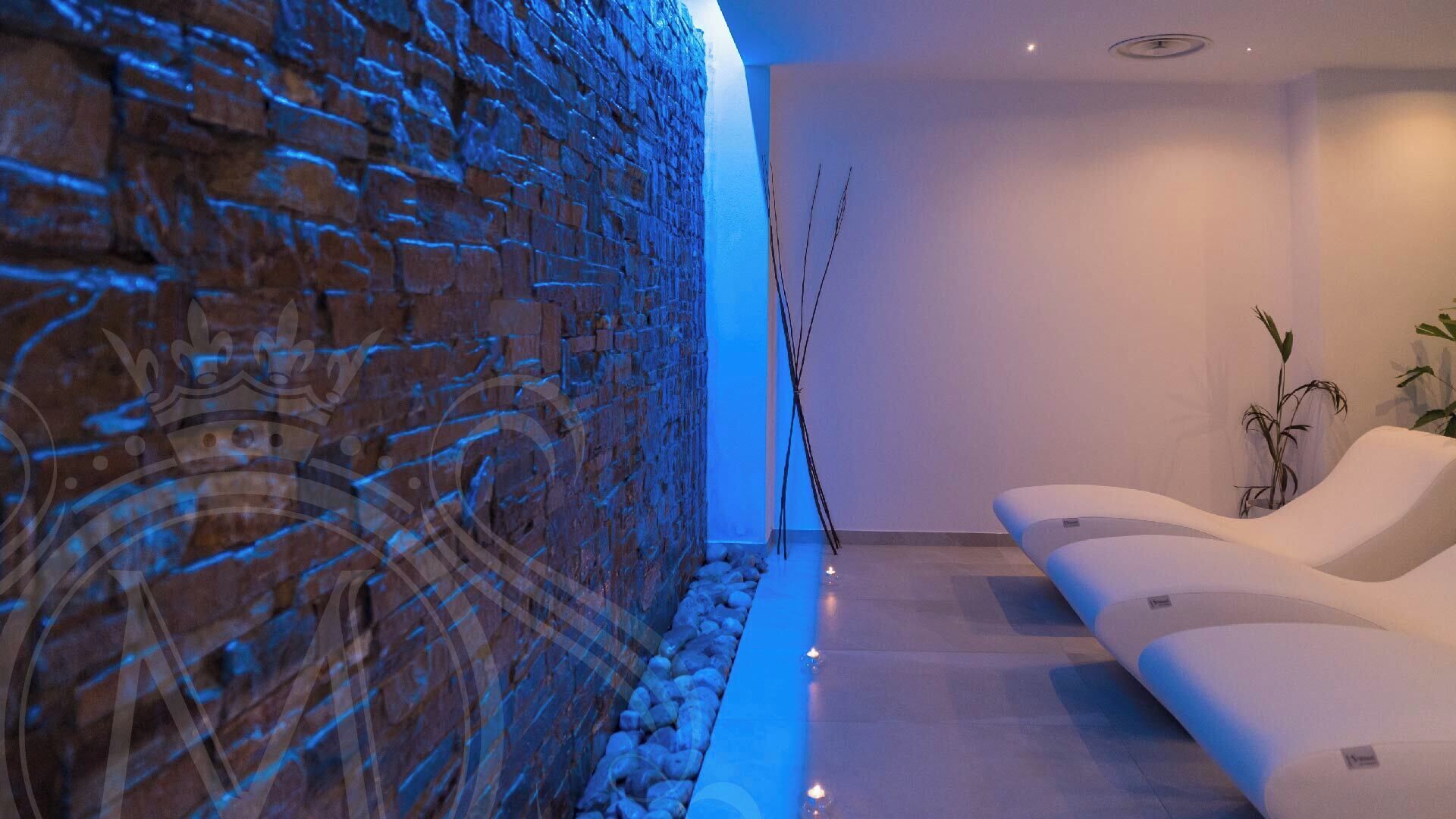 A modern spa area with a stone wall, a seating area, and a small water feature.