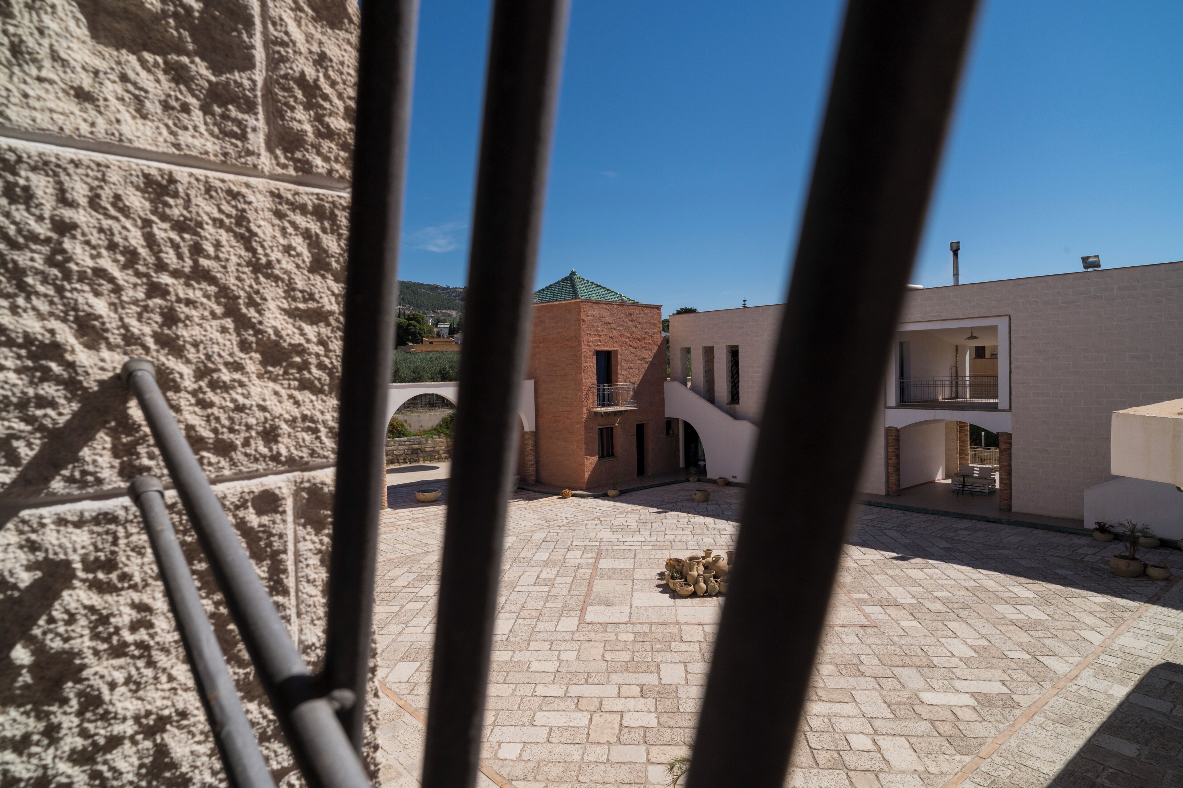 A courtyard with a stone floor, a brick building, and a metal railing.