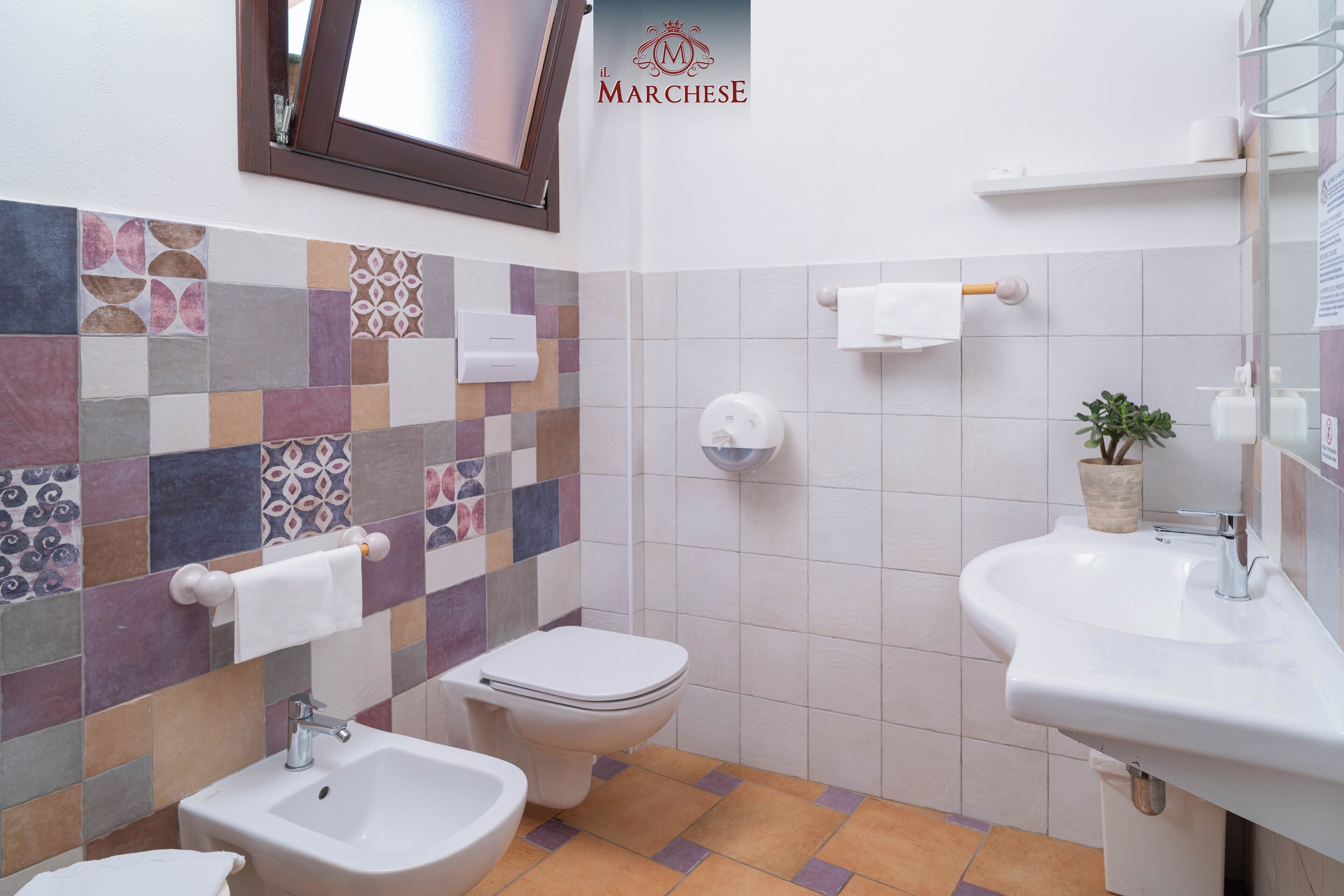 Un baño con salpicadero de azulejos, un inodoro, un bidé y un lavamanos.