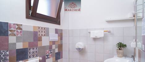 Un baño con salpicadero de azulejos, un inodoro, un bidé y un lavamanos.