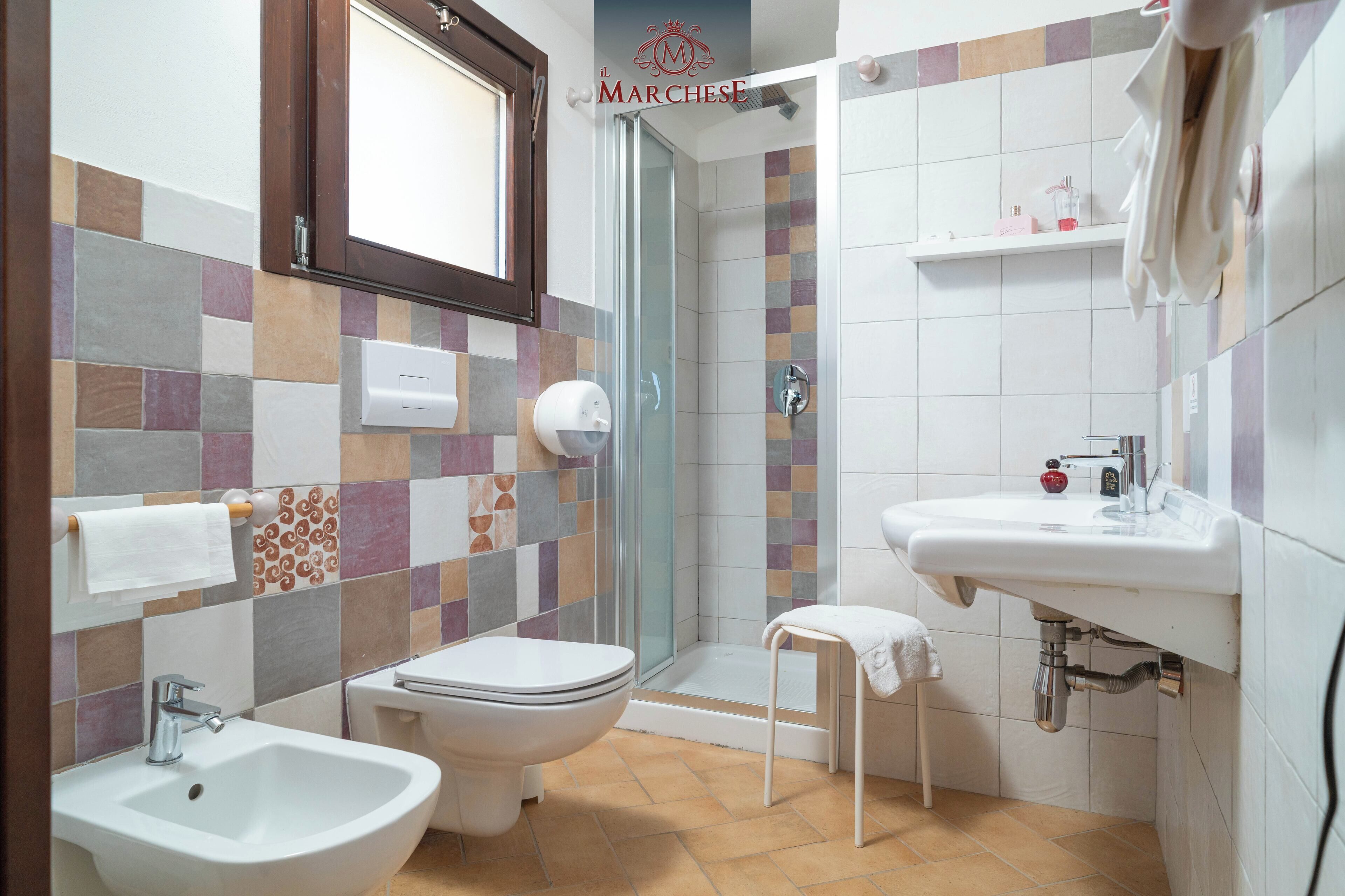 Un bagno con bidet, toilette, doccia e lavandino.