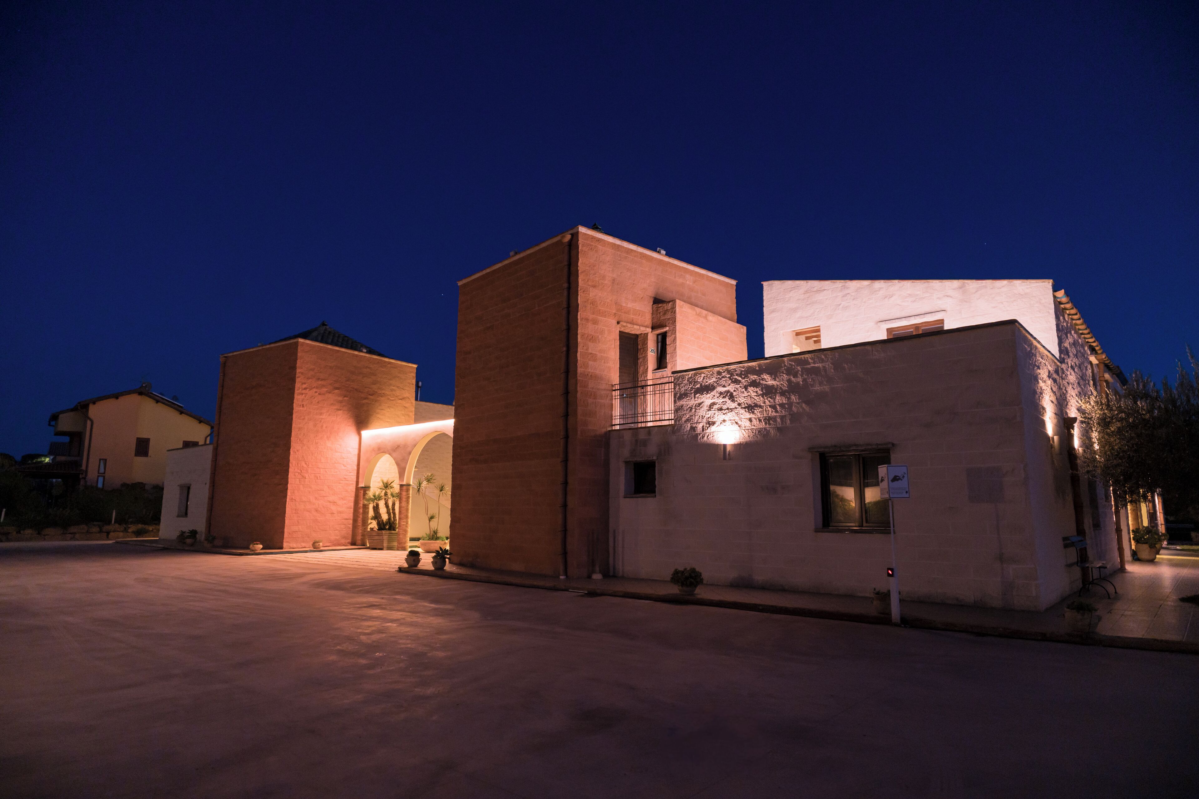 A building with a large open courtyard, a central archway, and a small balcony.