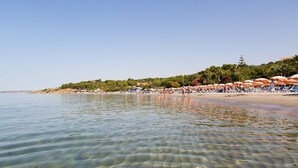 A beach with clear shallow waters, umbrellas, and people. - Il Marchese Hotel & Spa (Sciacca)