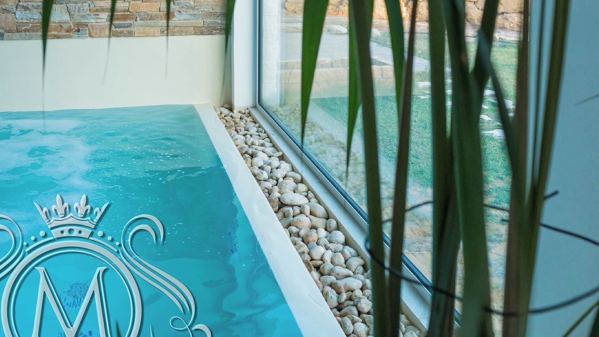 A spa area with a pool, a stone wall, and a window with plants.