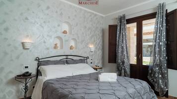 A bedroom with a bed, two bedside tables, a wall-mounted light, and a window with curtains.