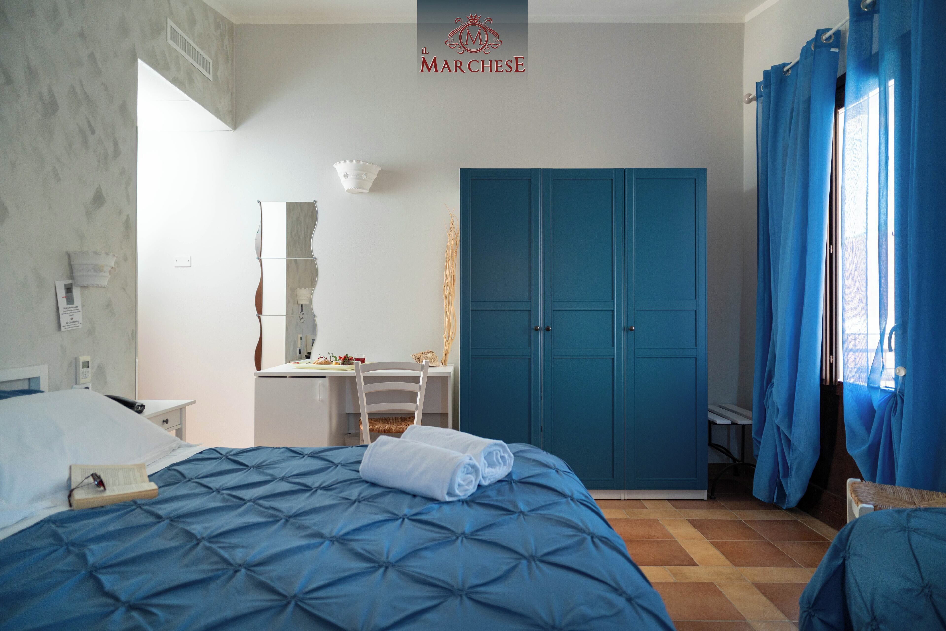 A hotel room with a bed, a desk, a wardrobe, and a bathroom.