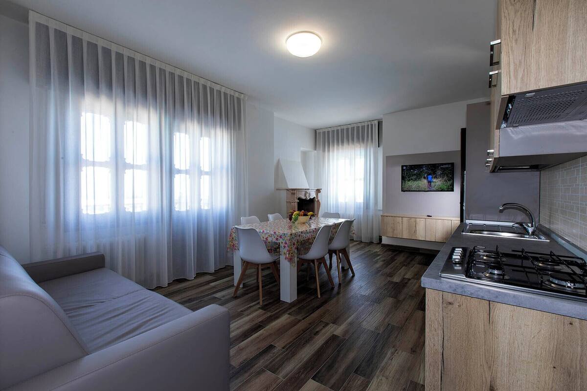 A modern kitchen with a gas stove, a dining area with a table and chairs, and a living area with a sofa.
