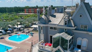 A hotel with a swimming pool, outdoor seating, and a large glass facade. - Camping Village Internazionale (Chioggia)