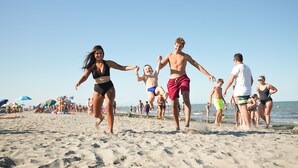 A sandy beach with people walking and playing. - Camping Village Internazionale (Chioggia)