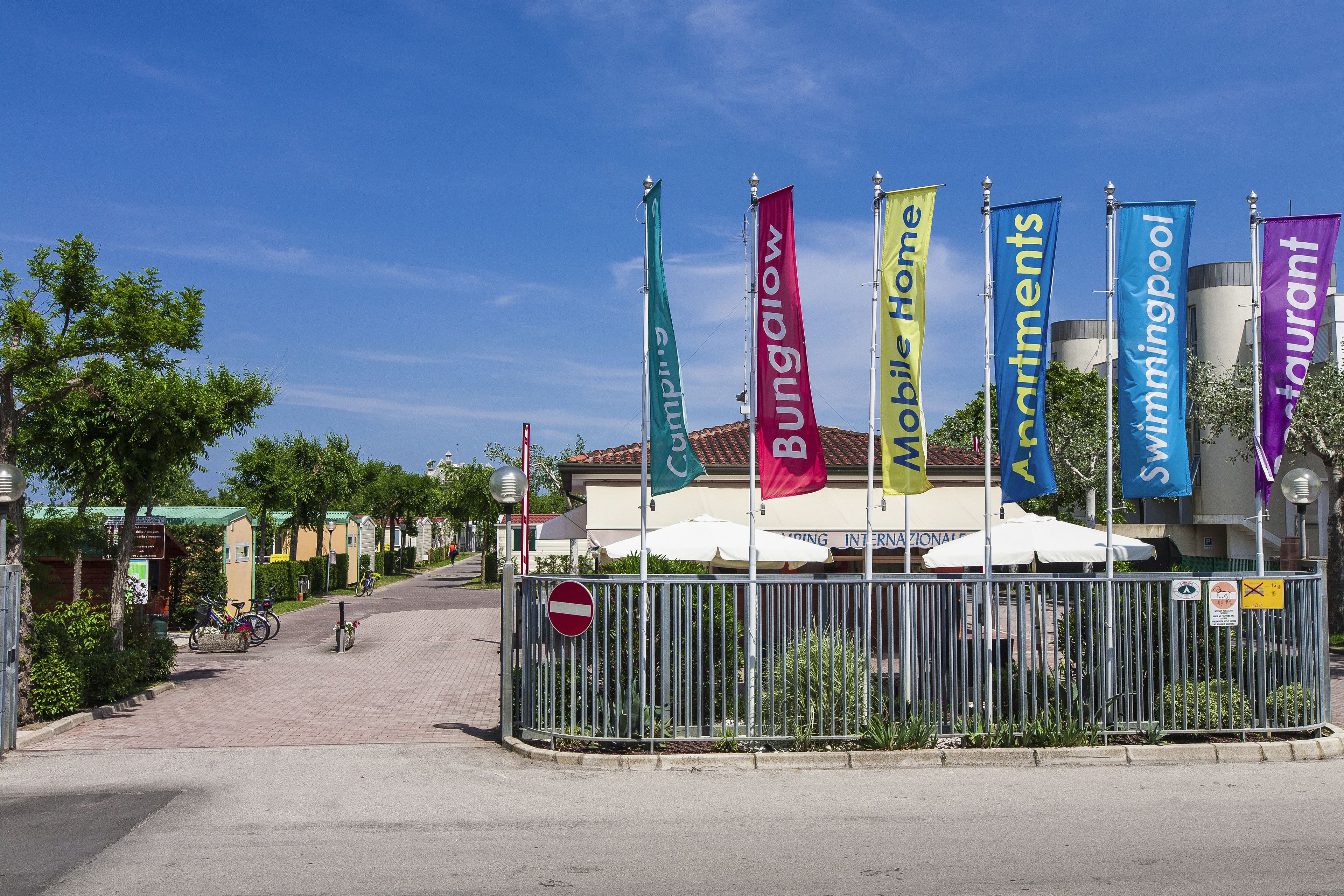 Et gadebillede med en række flag, der viser faciliteter såsom campingvogn, swimmingpool og restaurant.