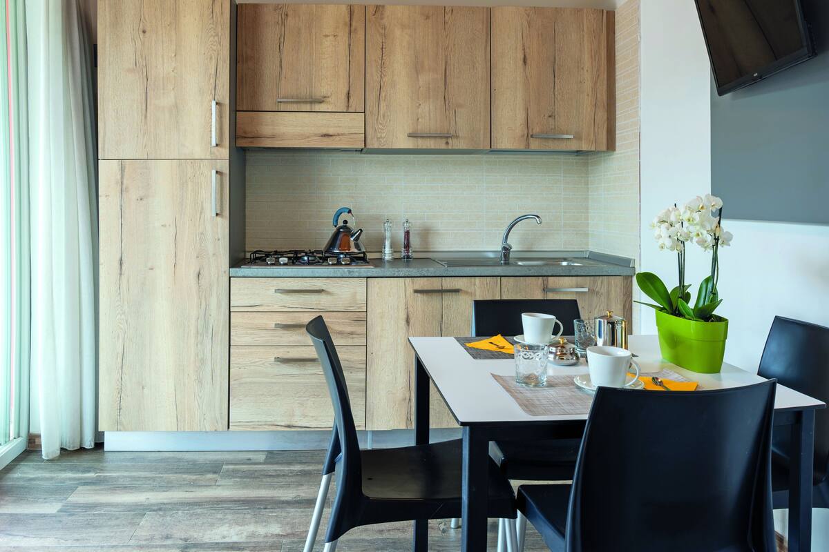 A modern kitchen with wooden cabinets, a gas stove, and a dining area with a table and chairs.
