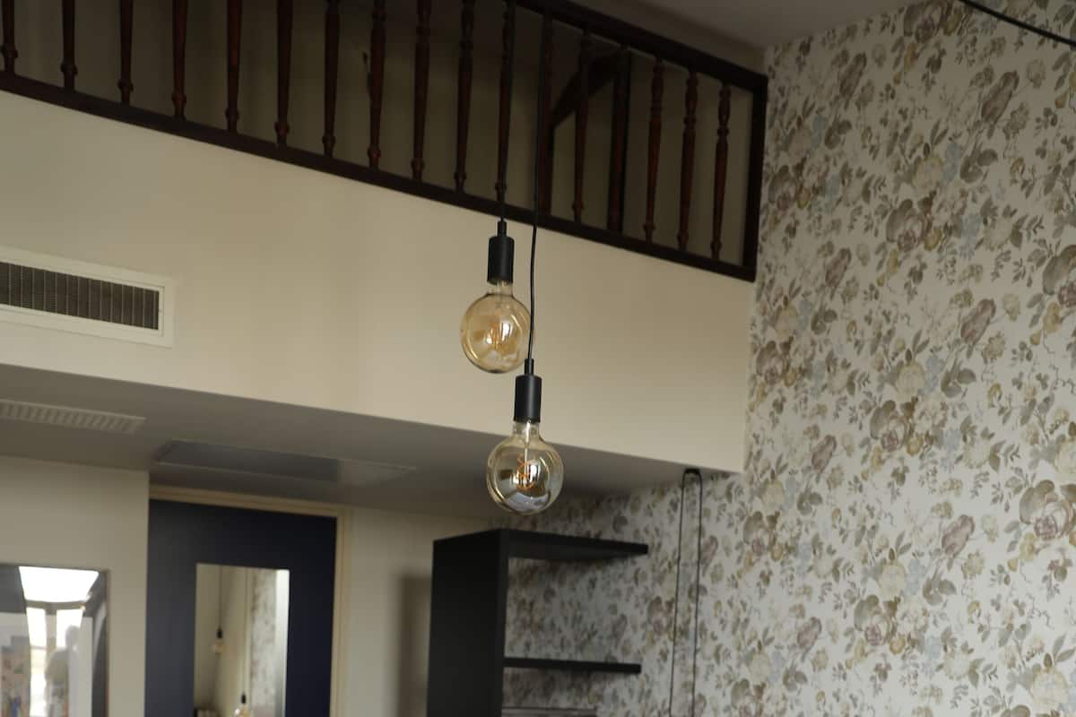 A hotel room with a large bed, a wooden ceiling, a floral wallpaper, and a door with a mirror.