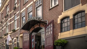 Entrada de un hotel con un cartel que dice "Courage Hotel" y un gran arco de entrada.