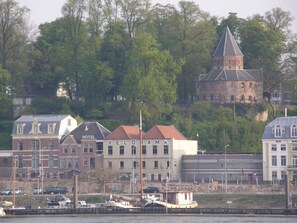 A waterfront hotel with a traditional European architectural style, featuring a prominent church in the background. - Hotel Courage Waalkade (Nijmegen)