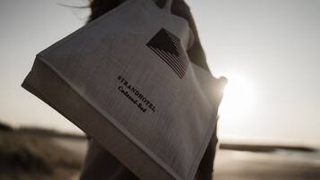 Une personne tenant un sac fourre-tout de marque sur lequel on peut lire l'inscription « STRANDHOTEL Cadzand-Bad ».