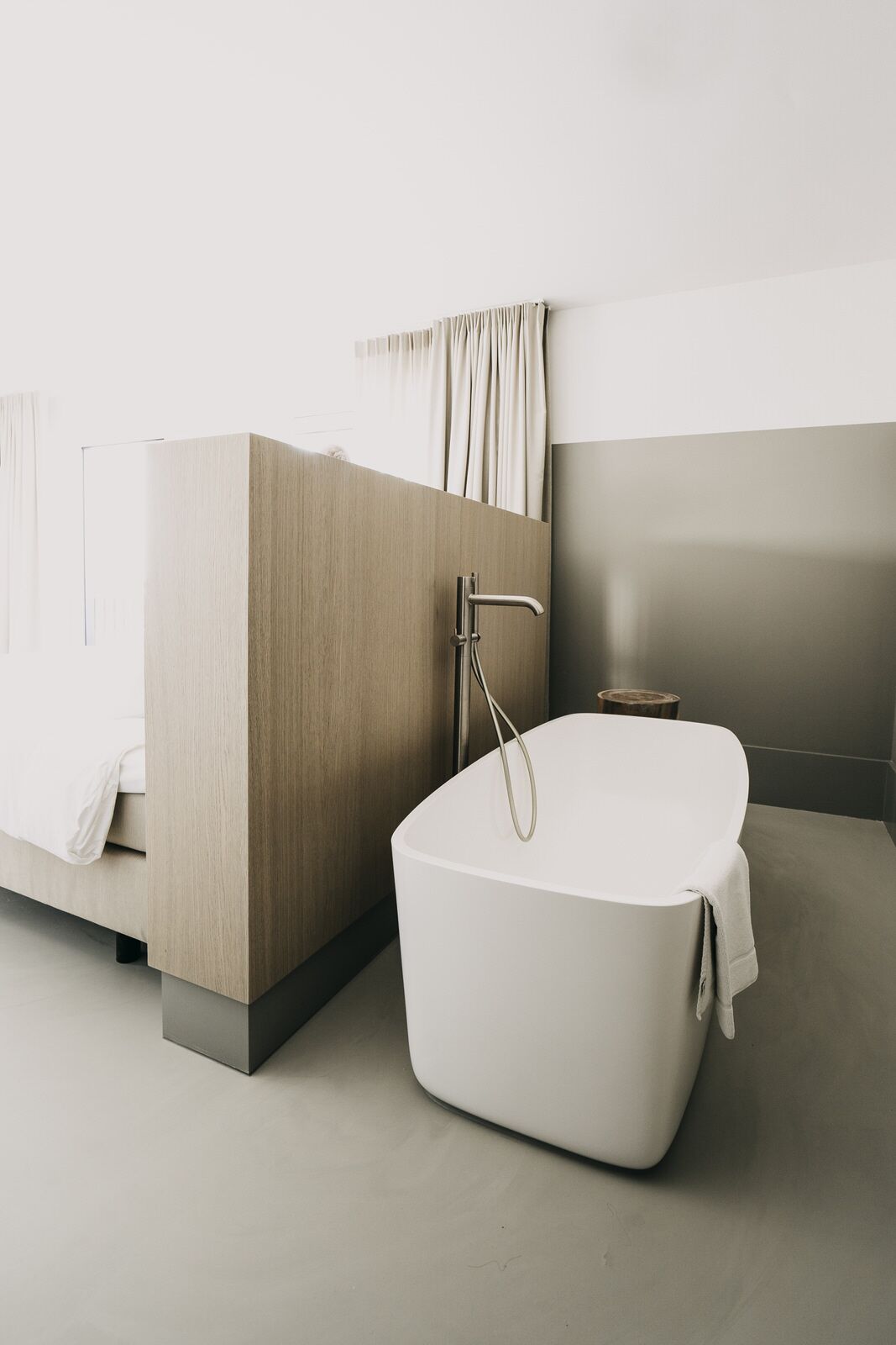 Un baño moderno con una bañera independiente, un tocador de madera y un espejo grande.