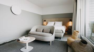 Une chambre d’hôtel moderne avec un lit, un canapé, une petite table et une grande fenêtre.
