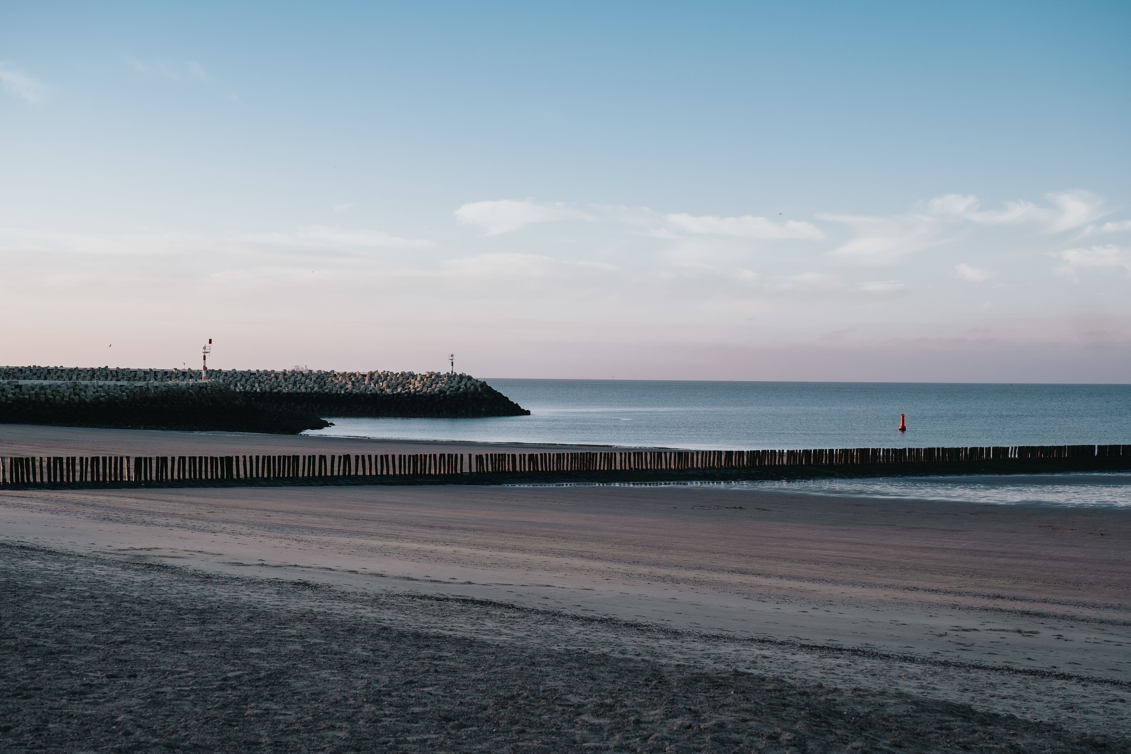 A beach with a wooden walkway leading to a rocky outcrop.
