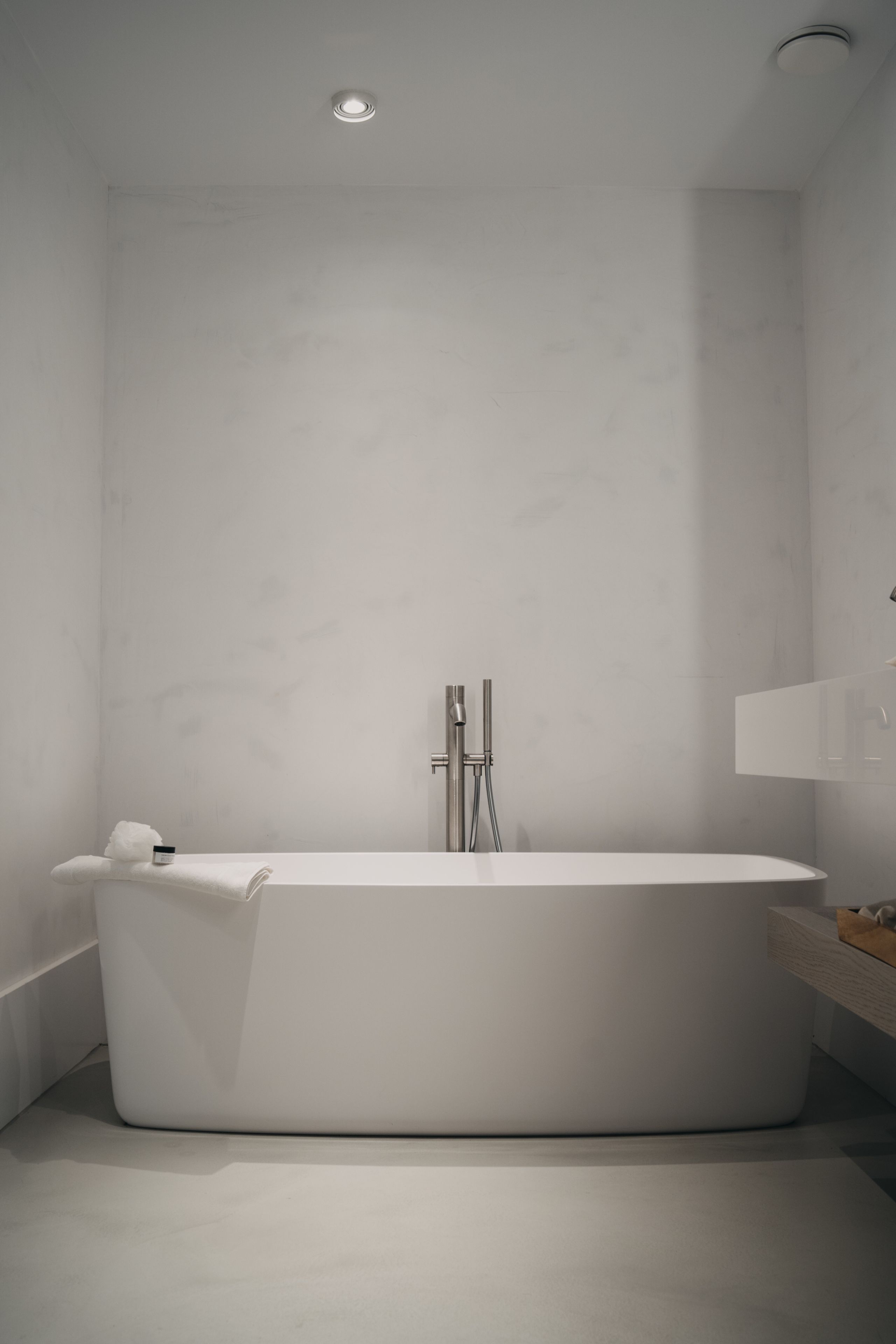 A modern bathroom with a freestanding bathtub, a towel rack, and a minimalist design.
