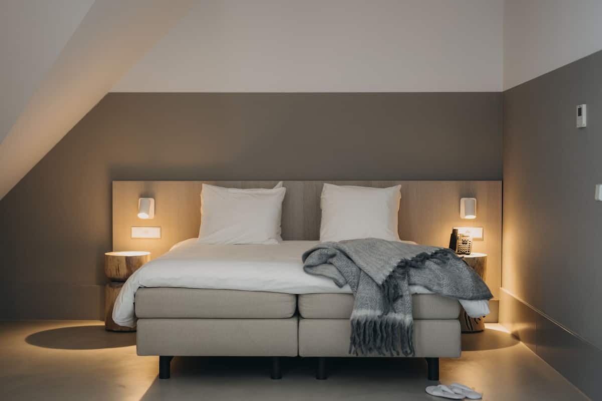 Un dormitorio moderno con una cama grande, dos mesitas de noche y una lámpara en el techo.