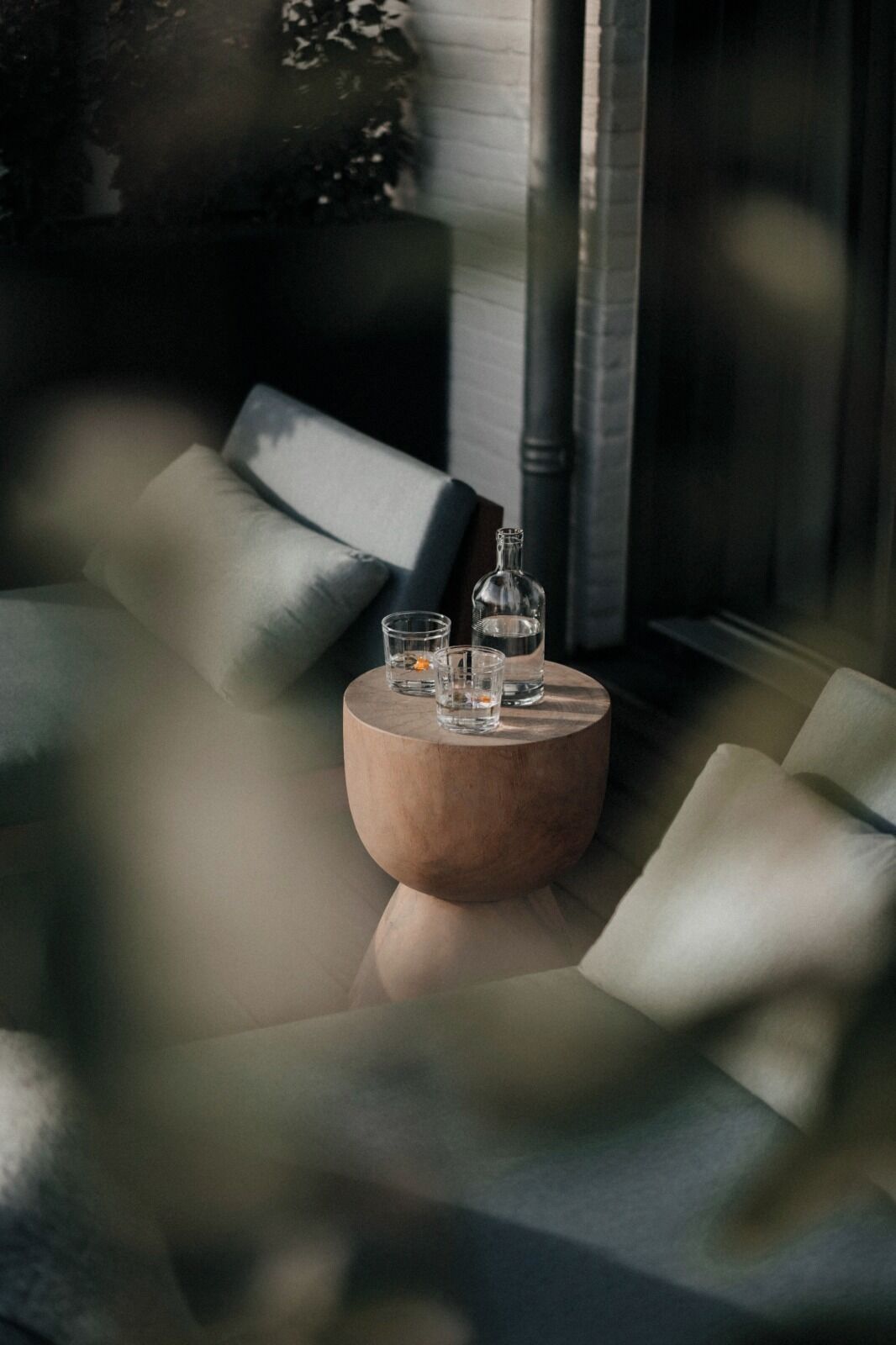 Un coin salon accueillant avec une table ronde en bois sur laquelle sont posés une bouteille et des verres.