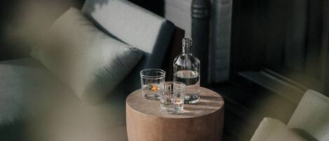 Un coin salon accueillant avec une table ronde en bois sur laquelle sont posés une bouteille et des verres.