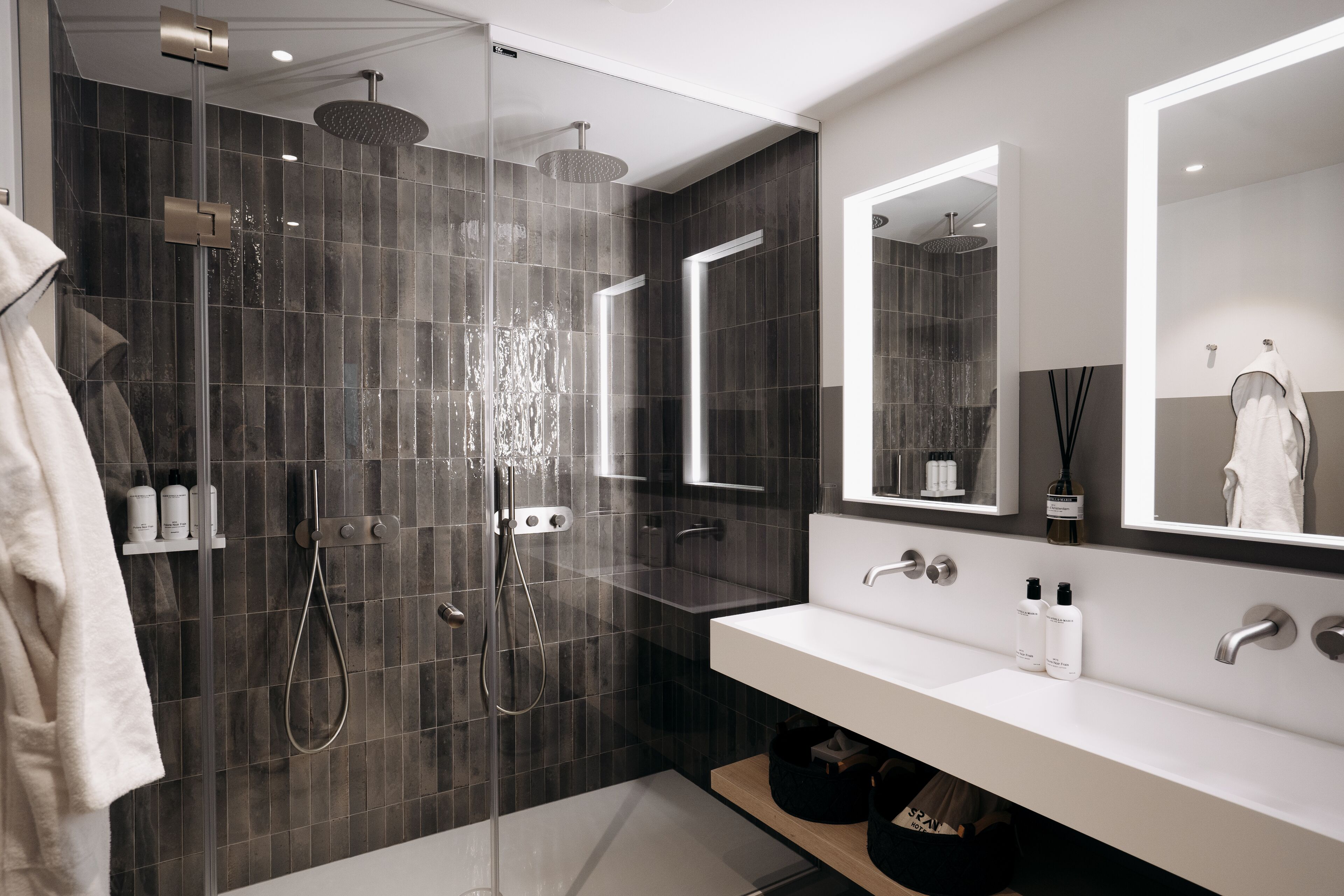 A modern bathroom with a glass-enclosed shower, a white sink, and a large mirror.