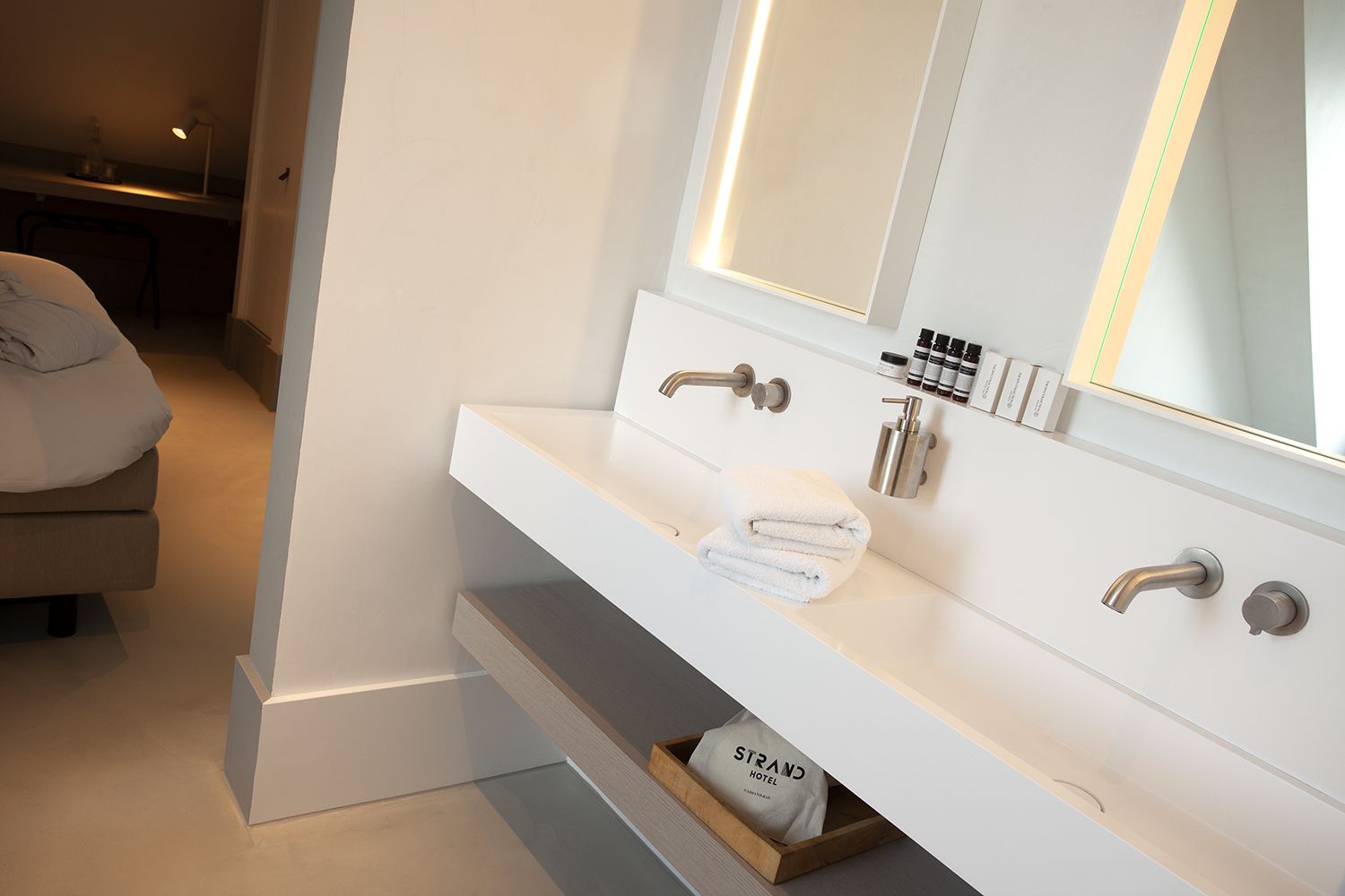 Een moderne badkamer met een witte wastafel, een grote spiegel en een handdoekrek.