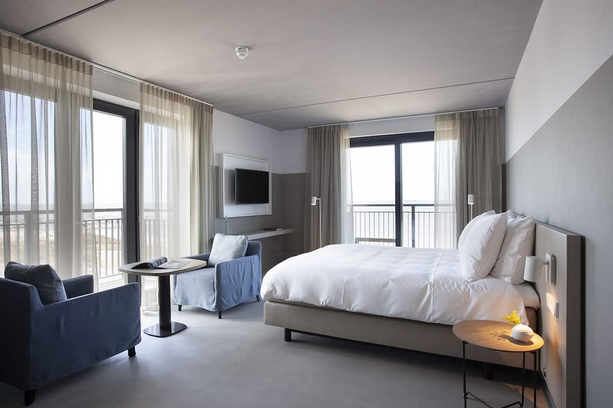Una habitación de hotel moderna con una cama grande, un escritorio, una silla y un televisor.