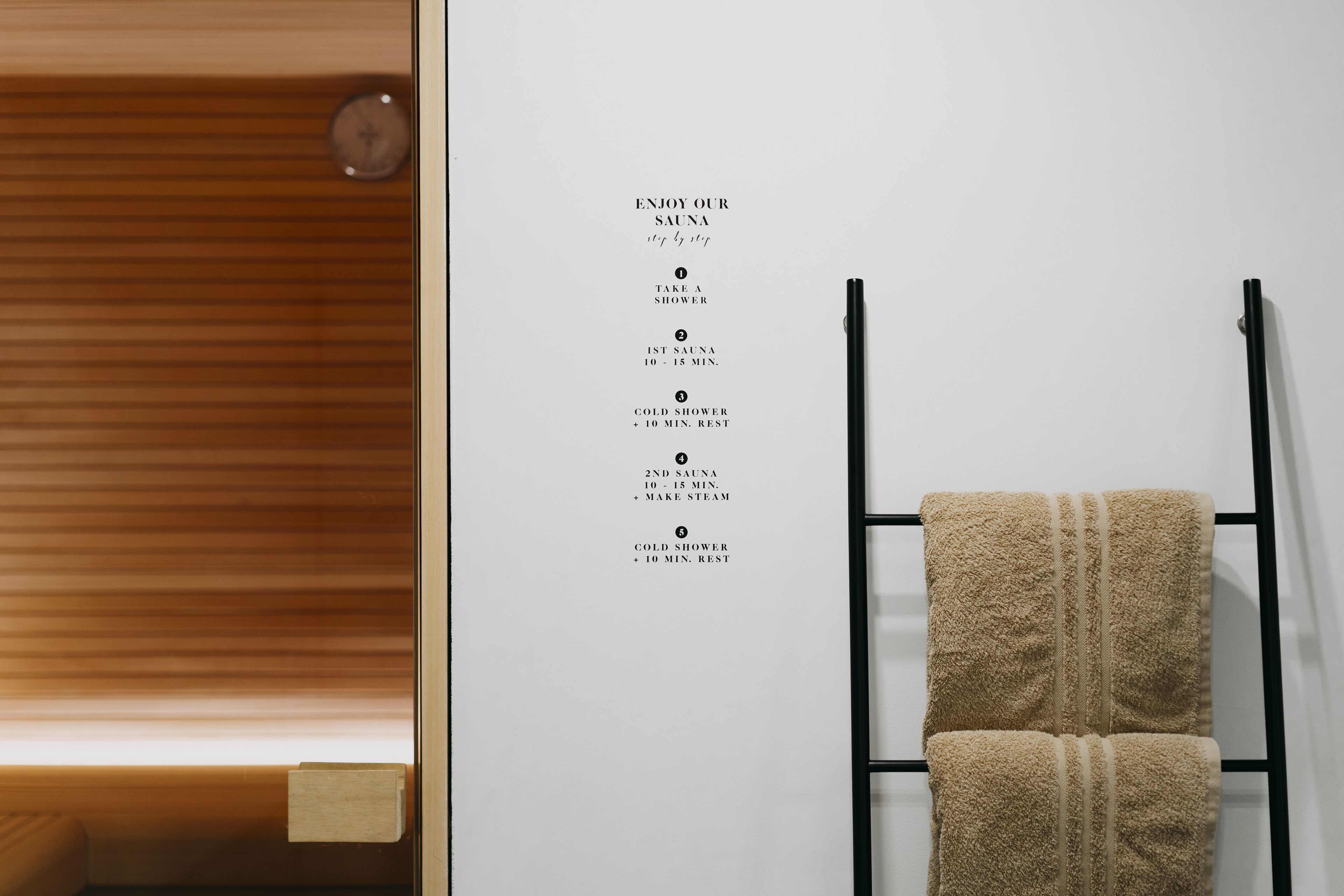 Eine Wand mit einem Saunatimeplan und einem Handtuchhalter mit Handtüchern.