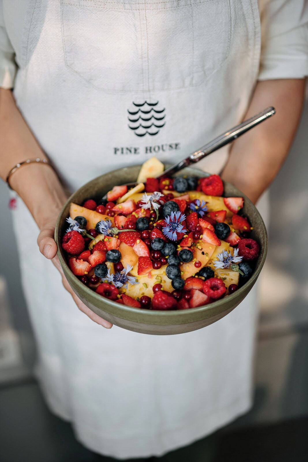 Iemand houdt een kom fruitsalade vast.